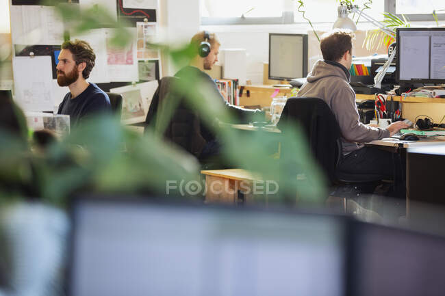 Творческие бизнесмены, работающие за компьютерами в офисе открытого плана — стоковое фото
