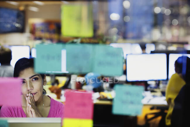 Nachdenkliche Geschäftsfrau blickt auf Klebezettel, Planung im Büro — Stockfoto
