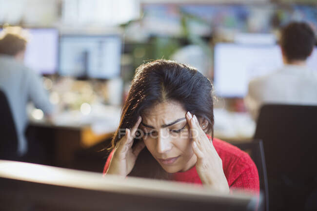 Стрессовая деловая женщина с головой в руках за компьютером в офисе — стоковое фото