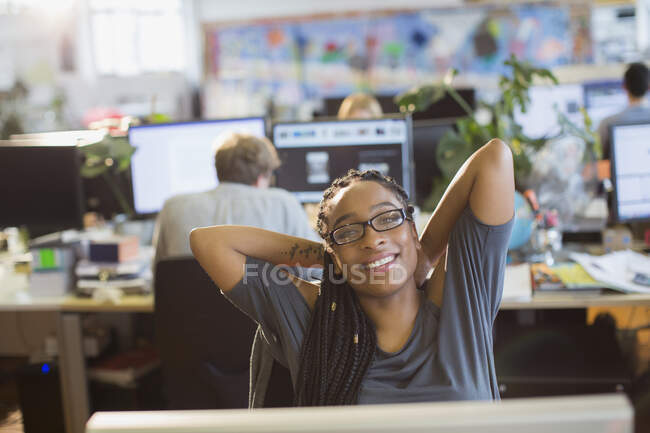 Портрет уверенной предпринимательницы растягивающейся в офисе открытой планировки — стоковое фото