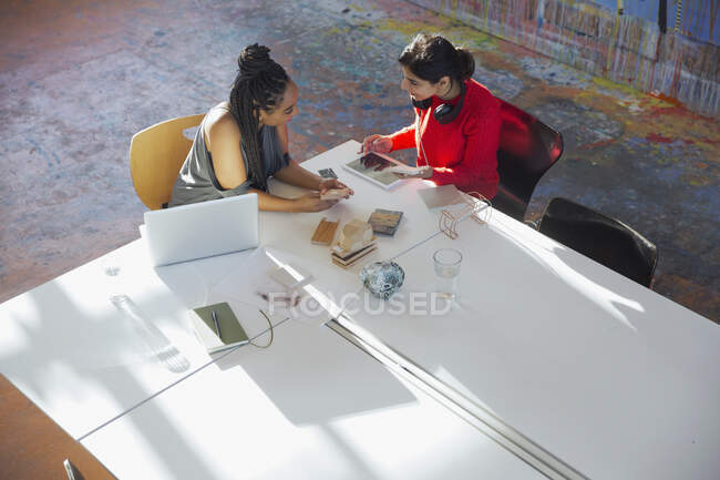 Creative businesswomen talking, using digital tablet, planning in conference room meeting — Stock Photo