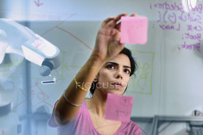 Сосредоточенное женское планирование инженера, использование клейких нот в офисе — стоковое фото