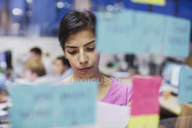 Pianificazione focalizzata della donna d'affari, utilizzando note adesive in ufficio — Foto stock