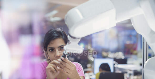 Focused female engineer with screwdriver fixing robotic arm — Stock Photo