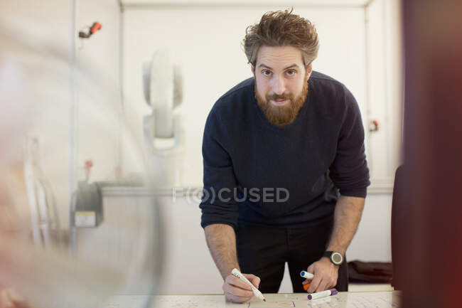 Ingeniero masculino confiado en retratos que planea en pizarra blanca en la oficina - foto de stock