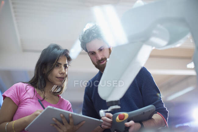 Engineers with digital tablet programming robotic arm in office — Stock Photo