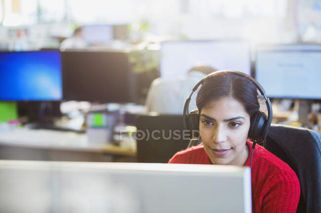 Бизнесмен с наушниками, работающая за компьютером в офисе — стоковое фото
