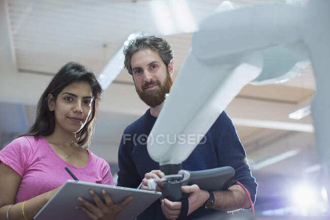 Ingegneri fiduciosi ritratto con braccio robotico di programmazione tablet digitale in ufficio — Foto stock