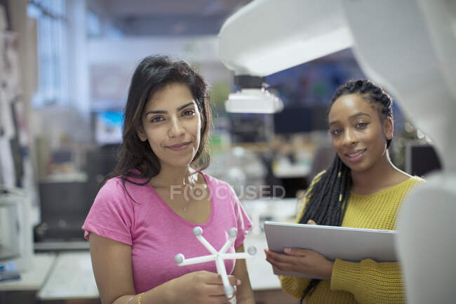 Портрет уверенных женщин-инженеров с прототипом и роботизированной рукой в офисе — стоковое фото