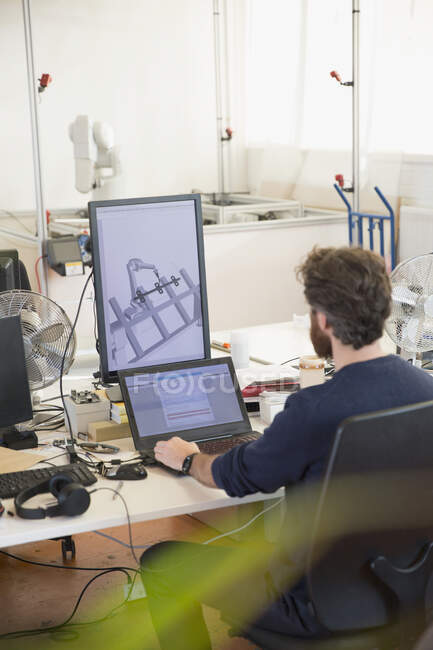 Männlicher Ingenieur programmiert Robotik, arbeitet im Büro am Laptop — Stockfoto