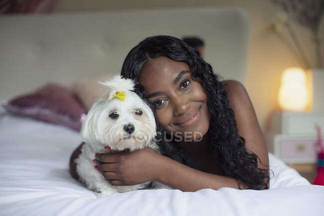 Portrait happy young woman with dog on bed — Stock Photo
