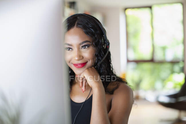 Giovane donna con auricolare che lavora da casa al computer — Foto stock