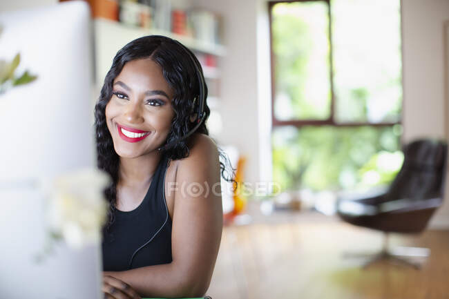 Happy young woman with headset working from home at computer — Stock Photo