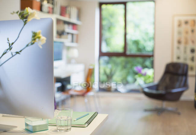 Computer and flowers on desk in home office — Stock Photo