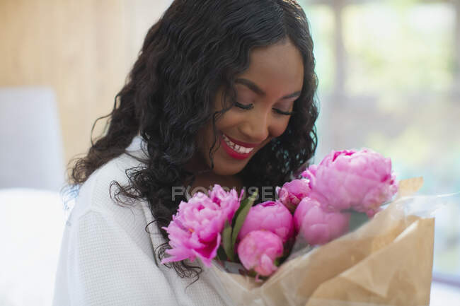 Jeune femme heureuse recevant un bouquet de pivoines roses — Photo de stock