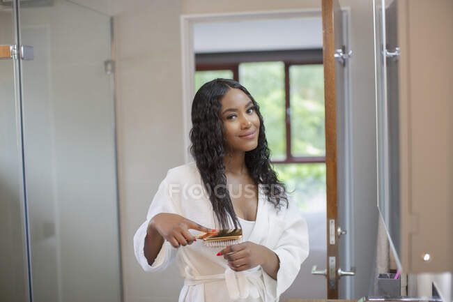 Retrato bonito sorrindo jovem mulher escovar o cabelo no banheiro — Fotografia de Stock