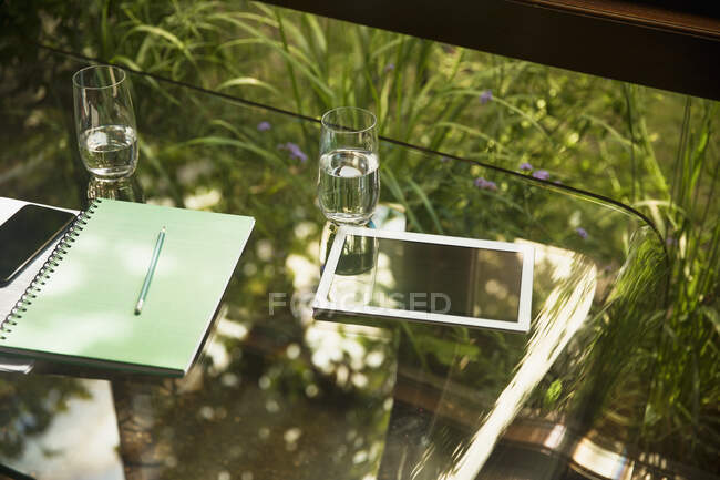 Цифровой стол и стаканы воды на стеклянном столе — стоковое фото