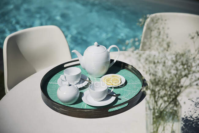 Servizio tè sul soleggiato tavolo patio a bordo piscina — Foto stock