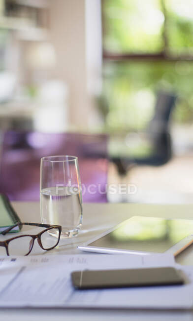 Водяне скло та окуляри на столі з паперовою роботою — стокове фото
