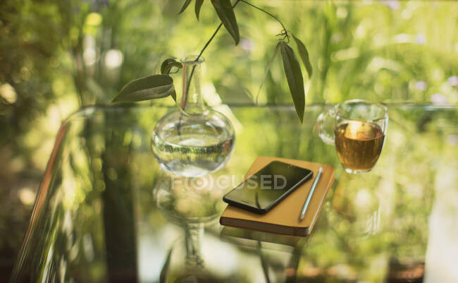 Tee und Smartphone auf dem Tisch mit Notizbuch und Vase — Stockfoto