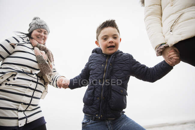 Portrait happy carefree boy with Down Syndrome holding hands with mom — Stock Photo
