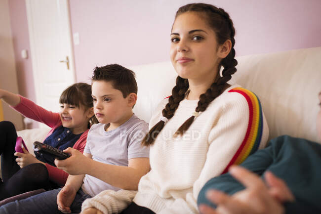 Portrait fille souriante regarder la télévision avec des frères et sœurs sur le canapé — Photo de stock