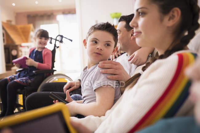 Niño con Síndrome de Down viendo televisión con su familia - foto de stock