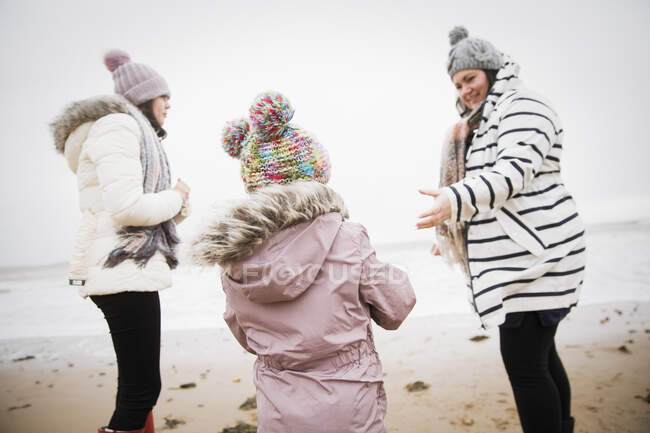 Familia en ropa de abrigo en invierno playa del océano - foto de stock
