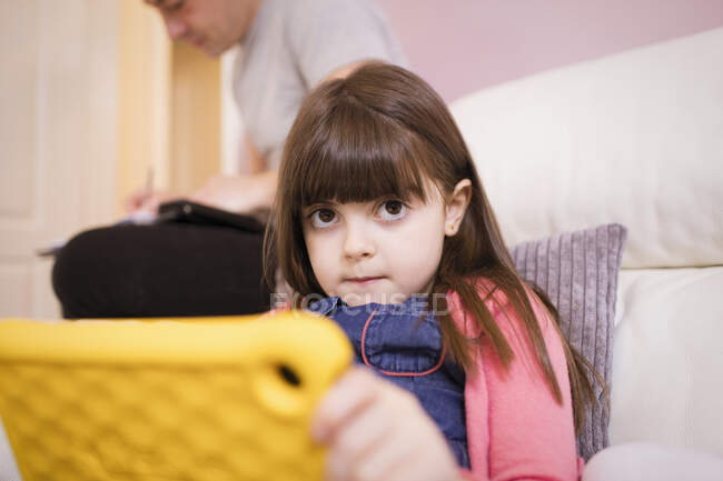 Retrato de chica inocente utilizando tableta digital en el sofá - foto de stock