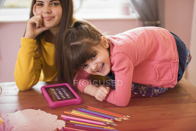 Retrato hermanas felices usando tableta digital en la mesa - foto de stock