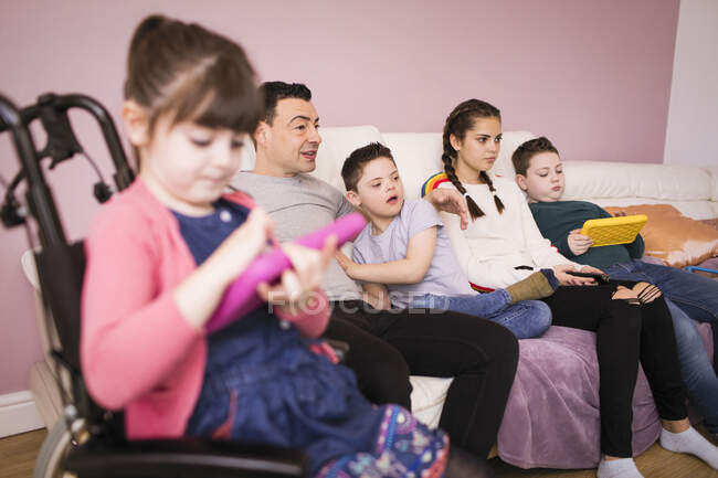 Down Syndrome família assistindo TV no sofá da sala de estar — Fotografia de Stock