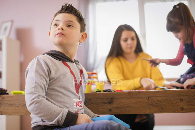 Neugieriger Junge mit Down-Syndrom spielt am Tisch — Stockfoto