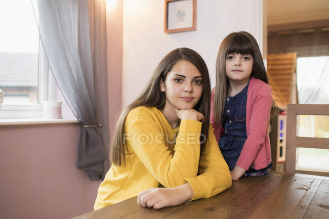 Portrait confident brunette sisters at dining table — Stock Photo