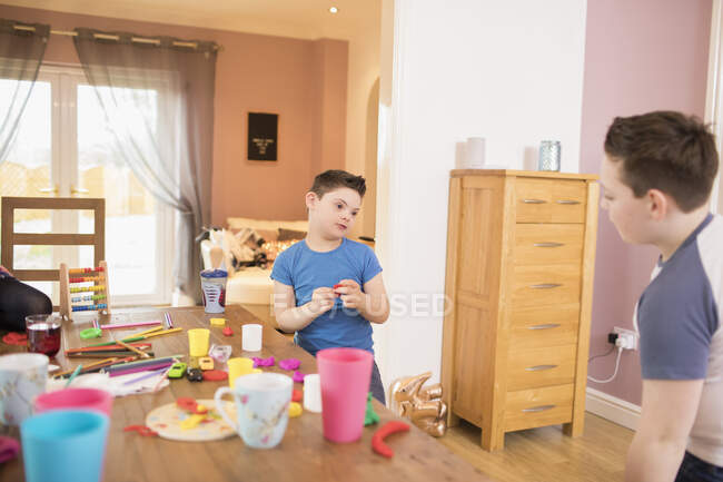 Парень с синдромом Дауна играет с игрушками за обеденным столом — стоковое фото