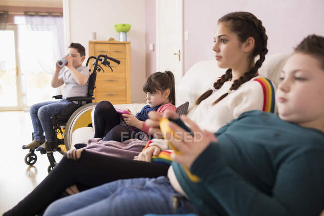 Братья и сестры смотрят телевизор на диване — стоковое фото