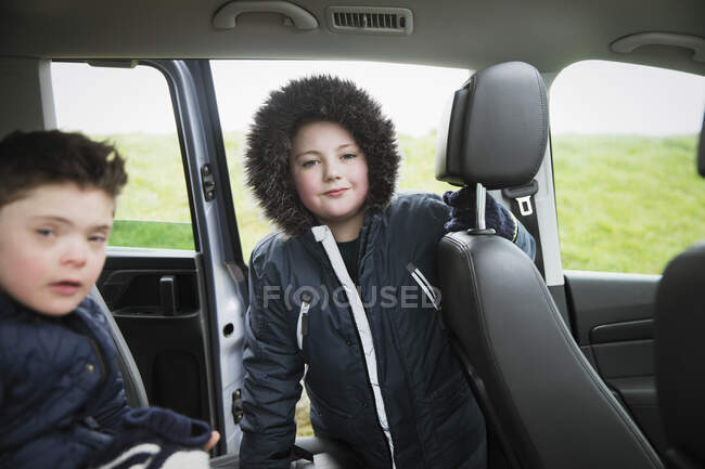 Portrait confident boy in fur hooded jacket in back seat of van — Stock Photo