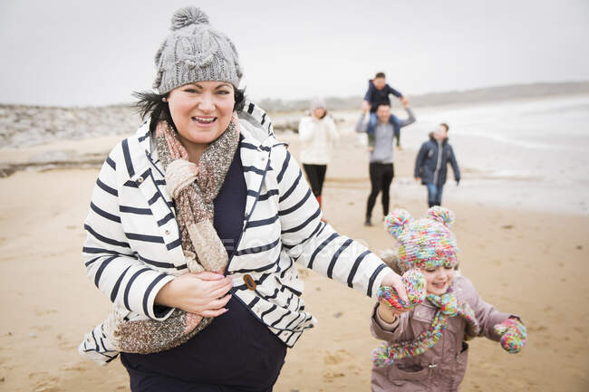 Retrato feliz mãe e filha correndo na praia de inverno — Fotografia de Stock