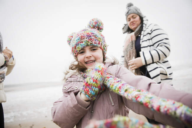 Porträt glückliches unbeschwertes Mädchen in warmer Kleidung am Winterstrand — Stockfoto