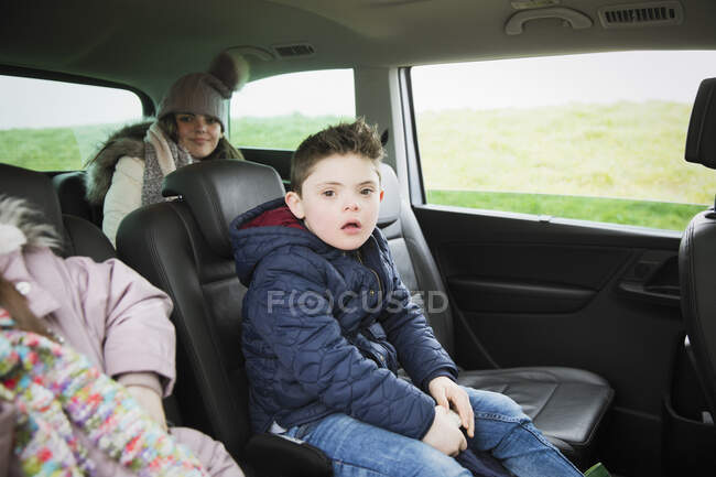 Портретний хлопчик з синдромом Дауна їде на задньому сидінні міні-фургона — стокове фото