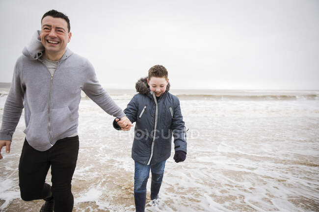 Happy father and son wading in winter ocean surf — Stock Photo