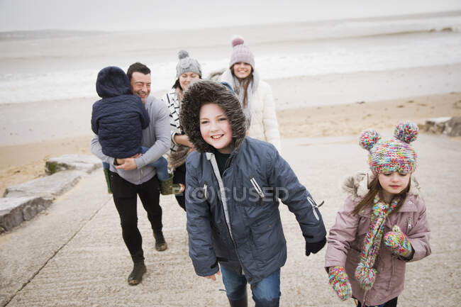Família feliz em roupas quentes andando até rampa de praia — Fotografia de Stock