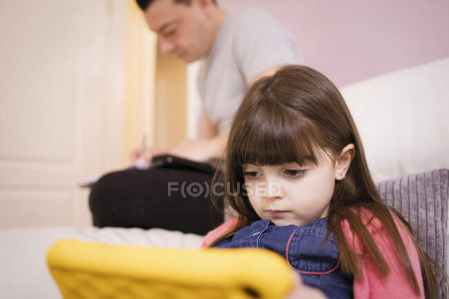 Chica enfocada usando tableta digital en el sofá - foto de stock