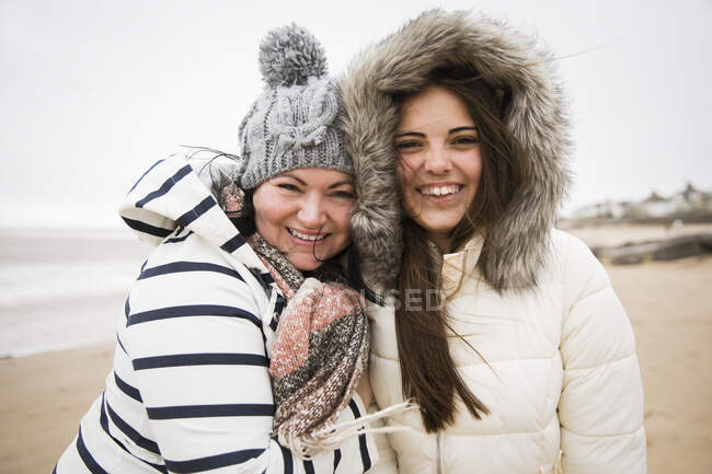 Retrato feliz madre e hija en ropa de abrigo en la playa - foto de stock