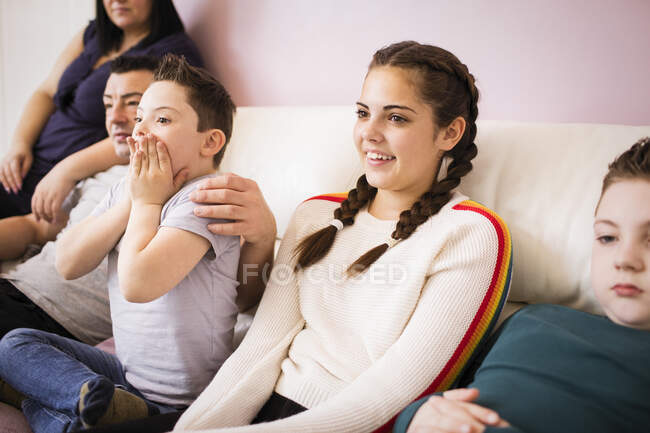 Happy family watching TV on living room sofa — Stock Photo