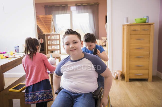 Retrato menino sorridente em cadeira de rodas em casa — Fotografia de Stock
