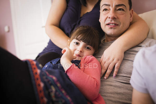 Happy girl cuddling with father on sofa — Stock Photo