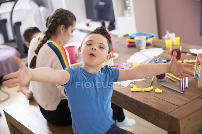 Retrato menino brincalhão com síndrome de Down jogando na mesa de jantar — Fotografia de Stock