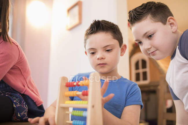 Хлопчик з синдромом Дауна і брат бавляться іграшками. — стокове фото