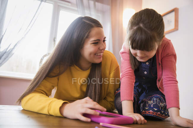Irmãs felizes usando tablet digital à mesa — Fotografia de Stock