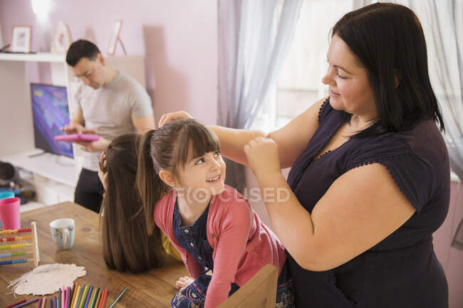 Glückliche Mutter fixiert Tochter Pferdeschwanz im Esszimmer — Stockfoto